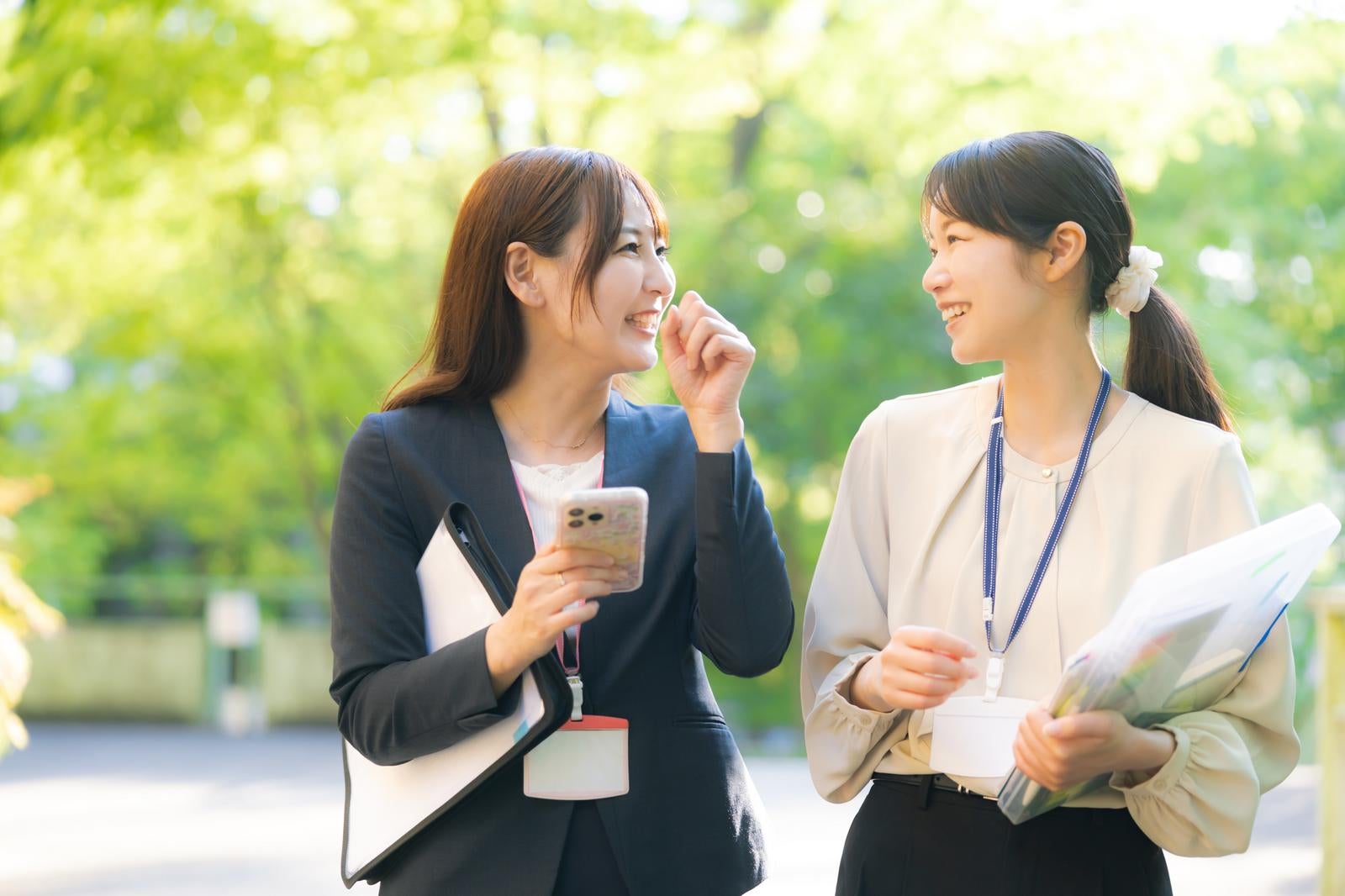 「新緑の中、会話が盛り上がる女性社員」の写真［モデル：あゆみん SAKI］