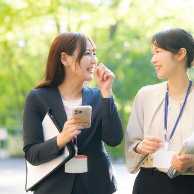 新緑の中、会話が盛り上がる女性社員の写真