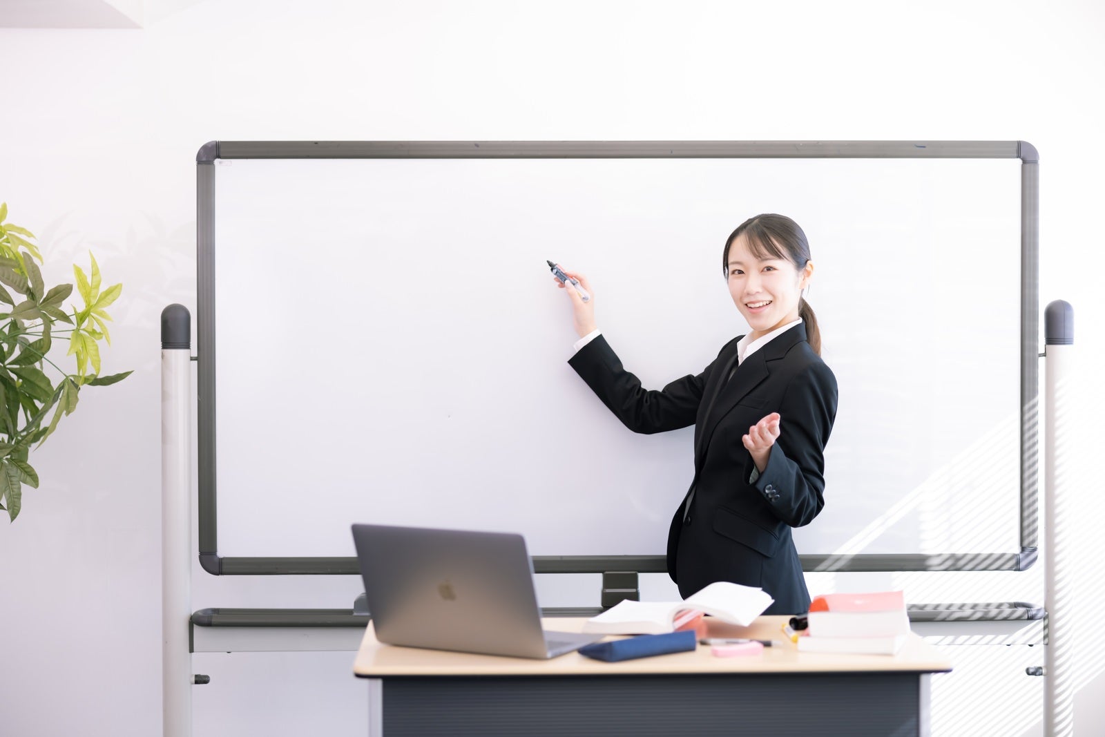 「ホワイトボードで説明する女性講師」の写真［モデル：SAKI］