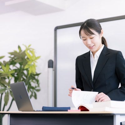 ホワイトボードの前で資料を説明する新人研修の女性講師の写真