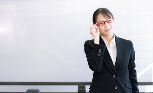赤い眼鏡に手をかける女性講師の写真