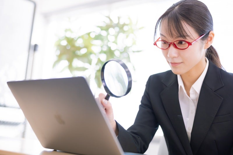 虫メガネを持つ女性社員の写真