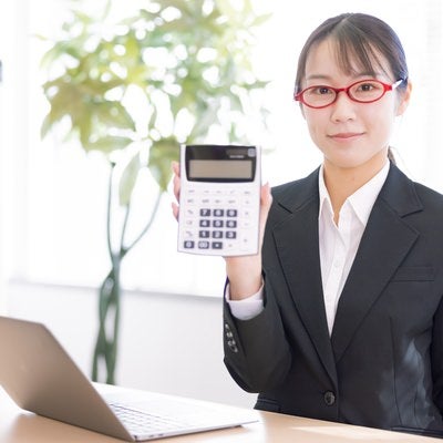 電卓をこちらに向ける女性会社員の写真