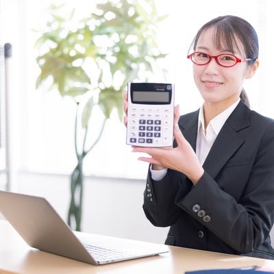 笑顔で電卓の商品説明する女性社員の写真