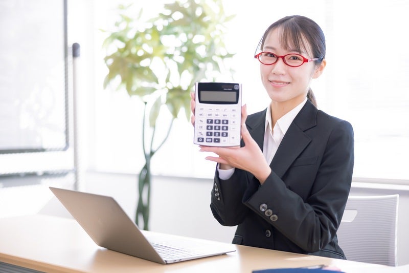 笑顔で電卓の商品説明する女性社員の写真