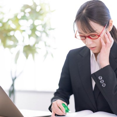 困り果てて修正テープを持つ女性の写真