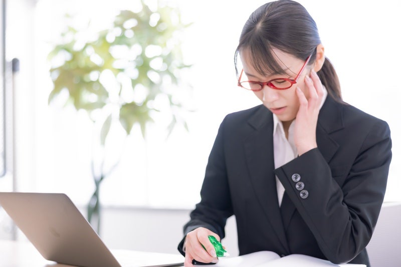 困り果てて修正テープを持つ女性の写真