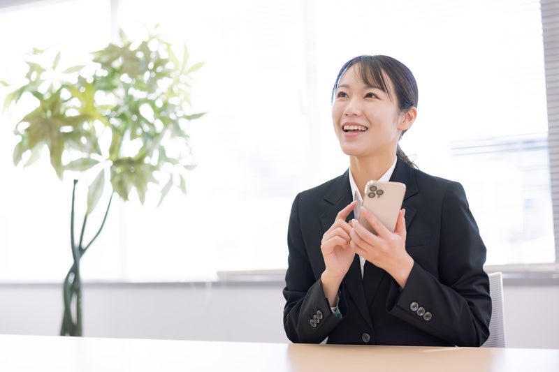 スマホを持って笑顔の新入社員