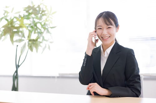 笑顔で通話する女性事務員の写真