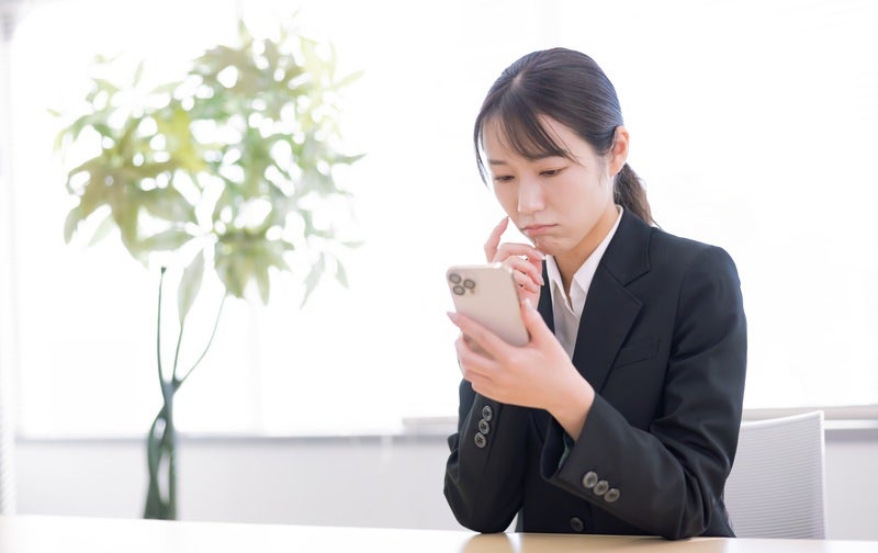 スマホ操作に戸惑う女性の写真
