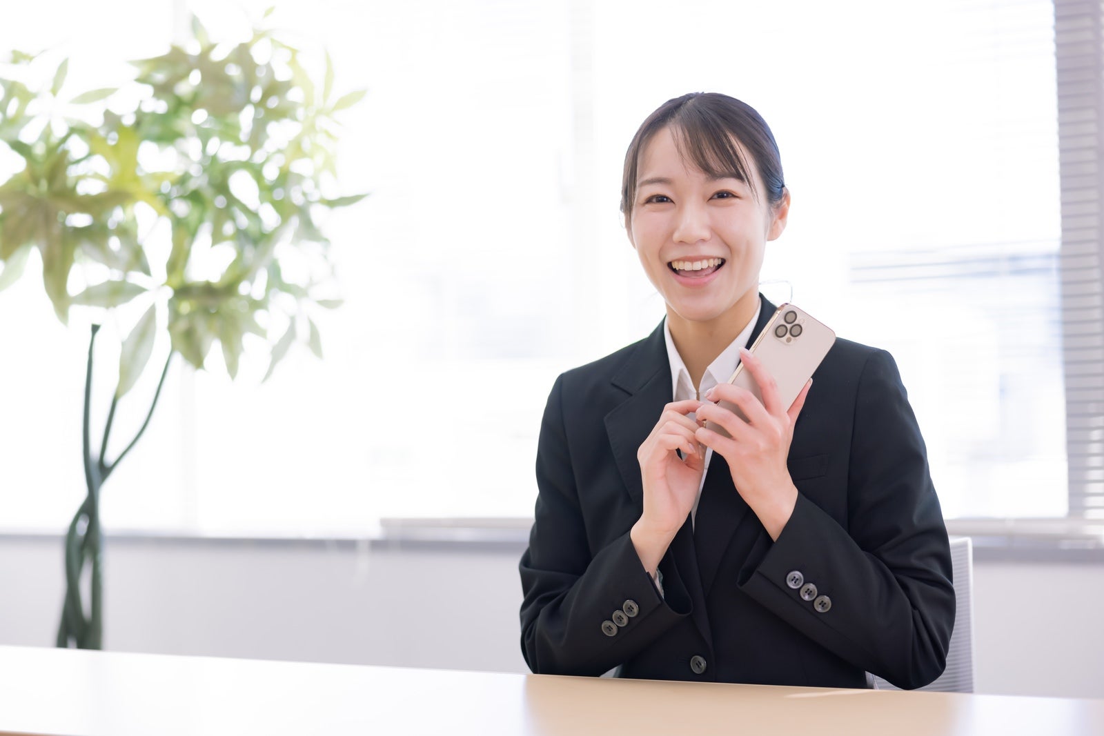 「スマホ片手に笑顔の女子社員」の写真［モデル：SAKI］