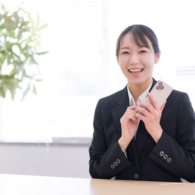 スマホ片手に笑顔の女子社員の写真