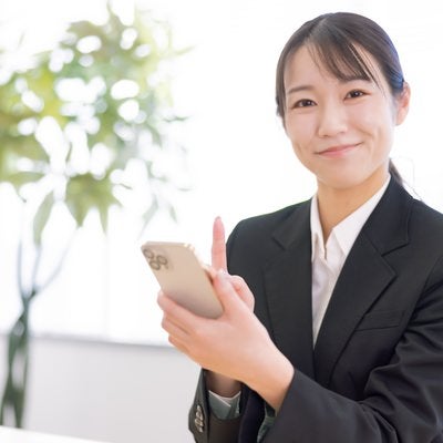 笑顔でスマホ操作をレクチャーしてくれる女性の写真