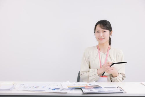 書類と会議室でメモを取る女性の写真