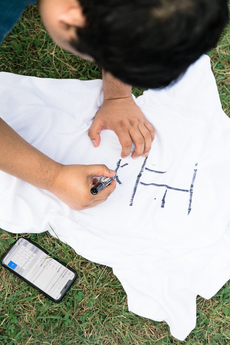 「Tシャツに正義の文字を書き込む」の写真［モデル：段田隼人］