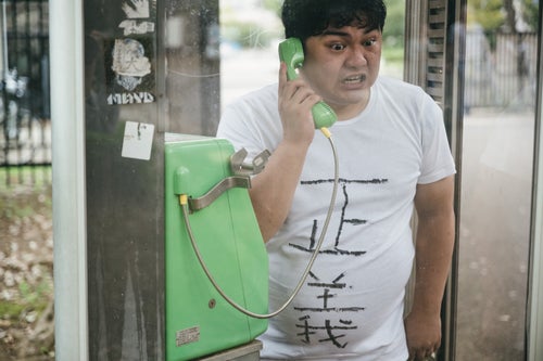 公衆電話から正義の通報をする男性の写真