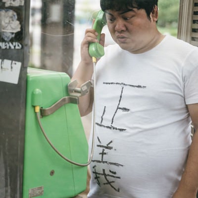 公衆電話から匿名のタレコミをする男性の写真