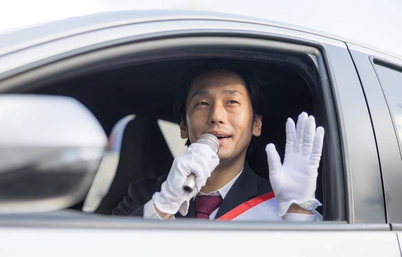 車窓から手を振る選挙人の写真