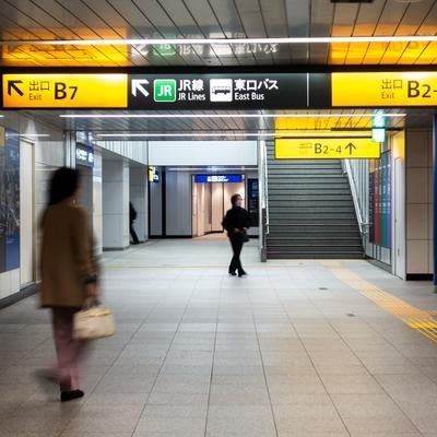 渋谷駅地下通路の案内板と通行人の写真