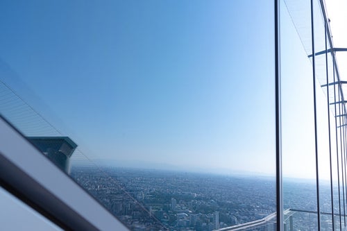 鏡のような窓に写り込む都市景観（渋谷スカイ）の写真