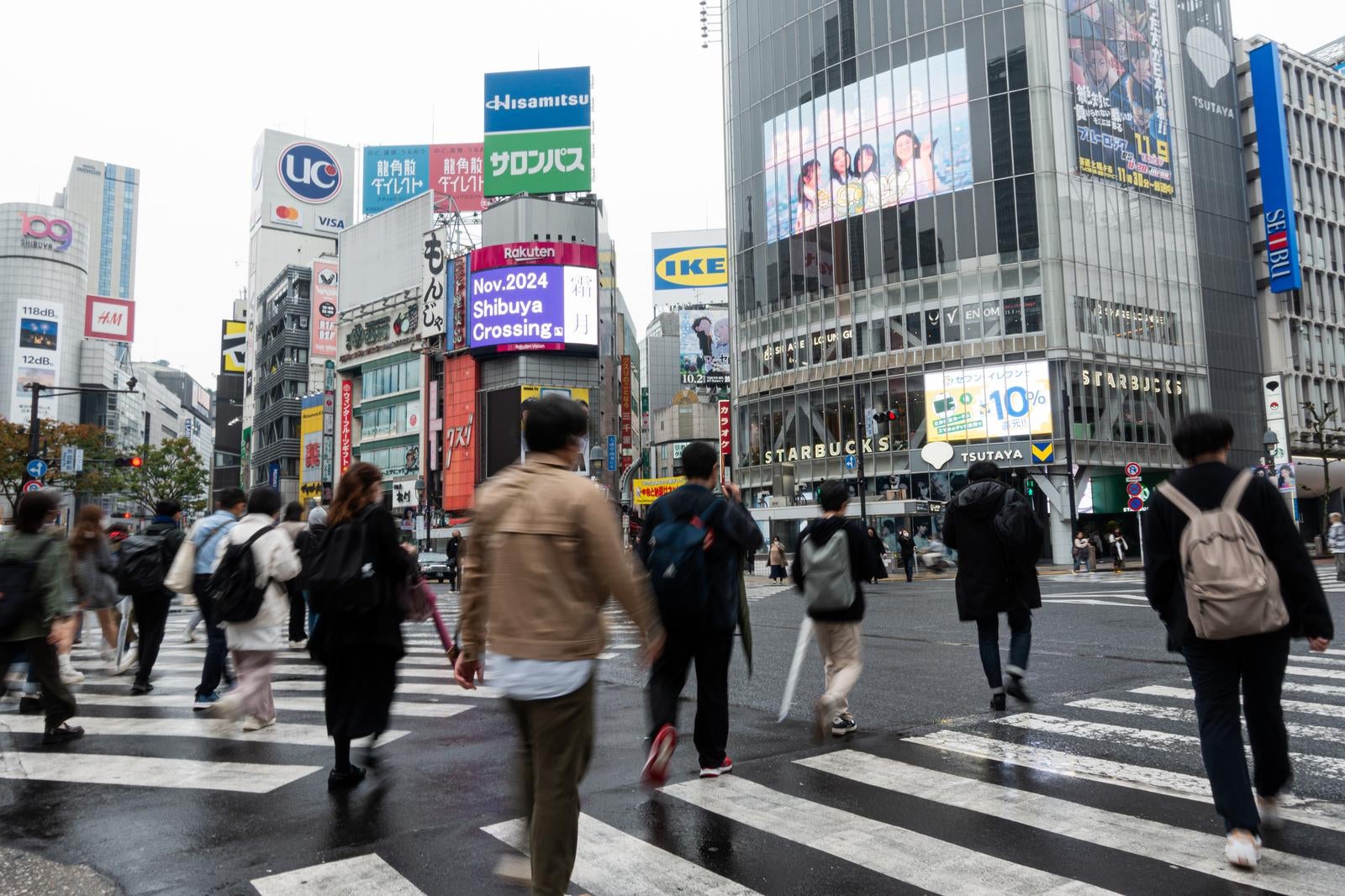 渋谷スクランブル交差点の横断歩道を渡る歩行者たちと周囲のビル看板群