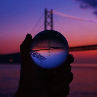 夕暮れ時のブリッジと反転して映る水晶球の写真