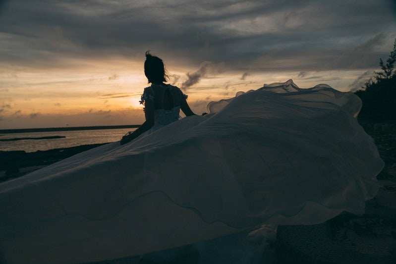 夕刻の砂浜とウェディングドレスを着た女性の写真