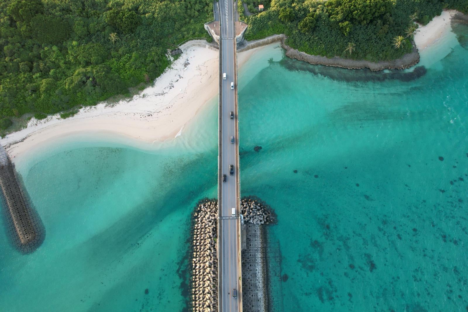 「透き通る海と白い砂浜に架かる橋」の写真