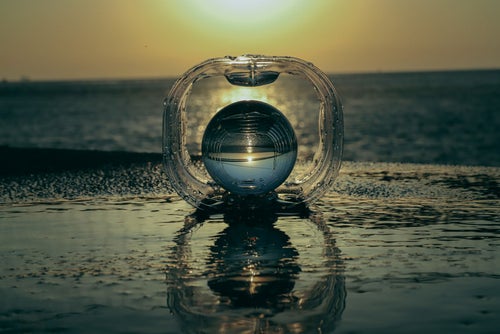 波打ち際のガラス玉と夕暮れの写真