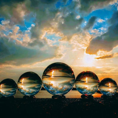 並んだ水晶玉と夕焼け空の写真
