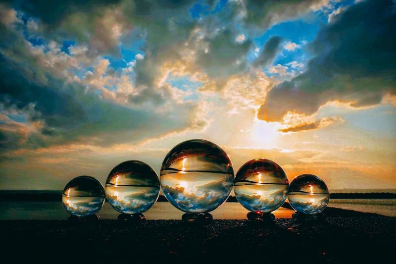 並んだ水晶玉と夕焼け空の写真