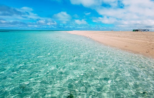 透明度の高い南国の海と波打ち際の白い砂の写真