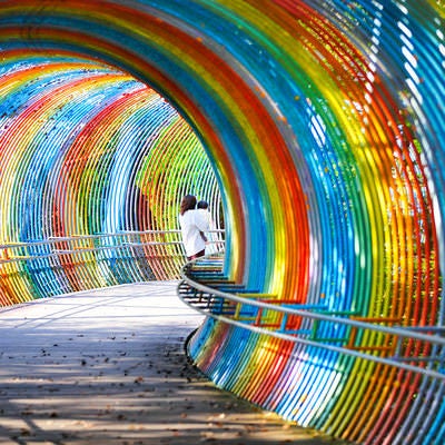虹色のトンネルを散歩する子供を抱えた女性の写真