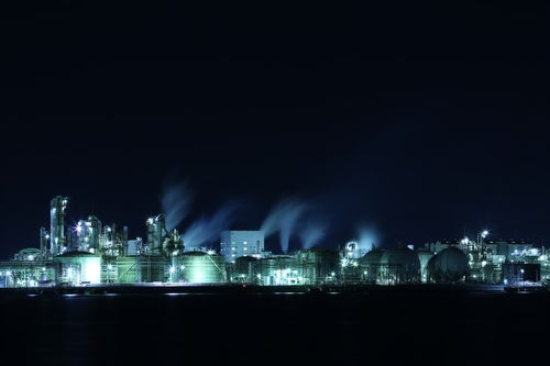暗闇に浮かぶ工場夜景の丸タンクの写真