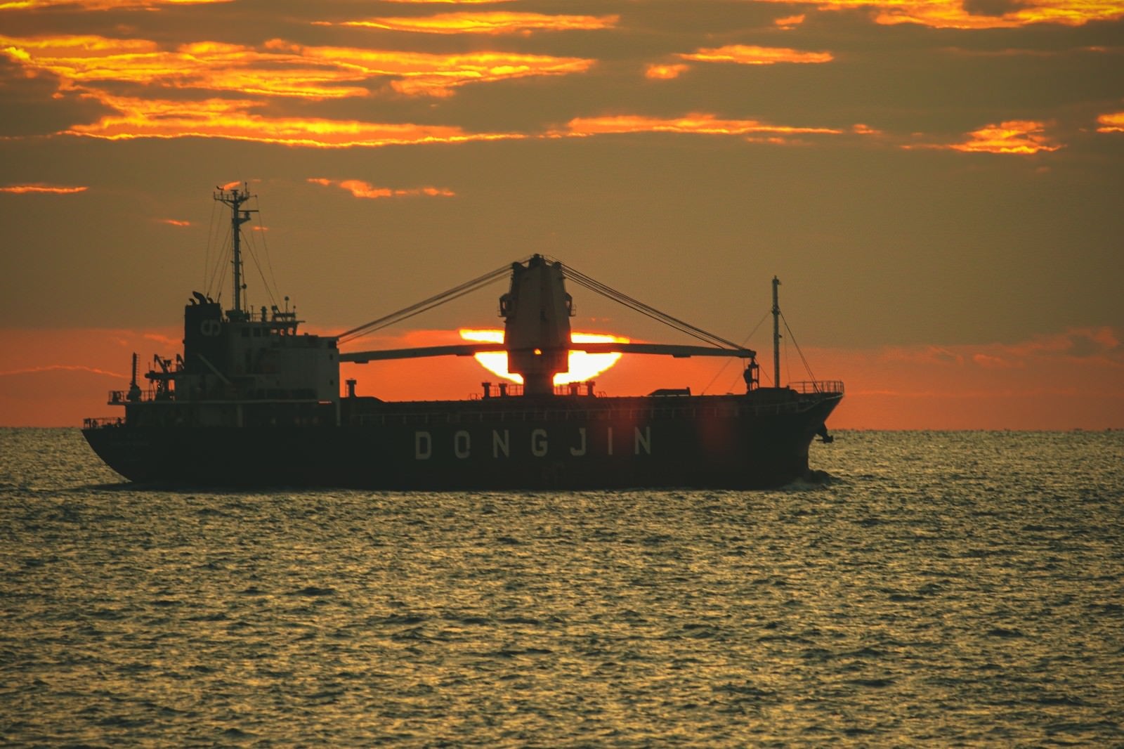 「夕日と重なる貨物船」の写真