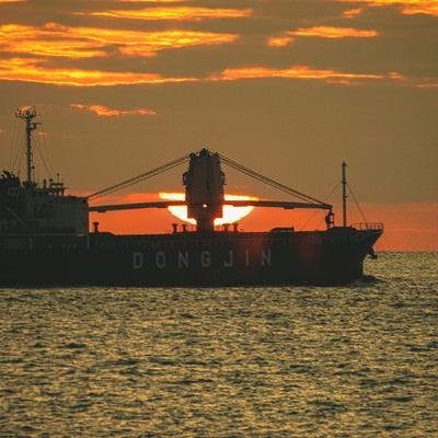 夕日と重なる貨物船の写真