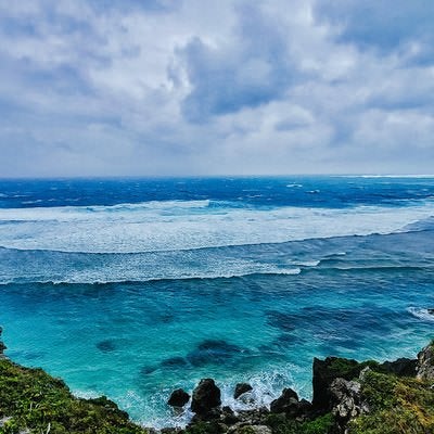 宮古島の海岸から望む白い波と青い海、エメラルドグリーンの浅瀬の写真