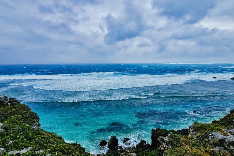 宮古島の海岸から望む白い波と青い海、エメラルドグリーンの浅瀬の写真