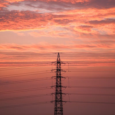 夕焼けに染まる雲と鉄塔の写真