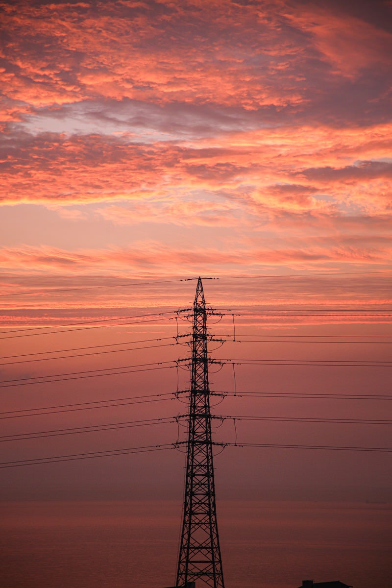 夕焼けに染まる雲と鉄塔の写真