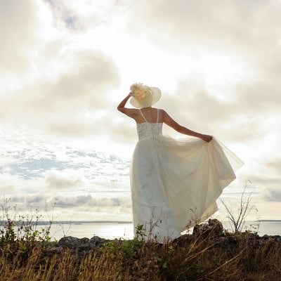 海岸線を眺めるドレス姿の女性の写真