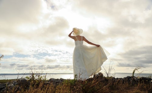 海岸線を眺めるドレス姿の女性の写真