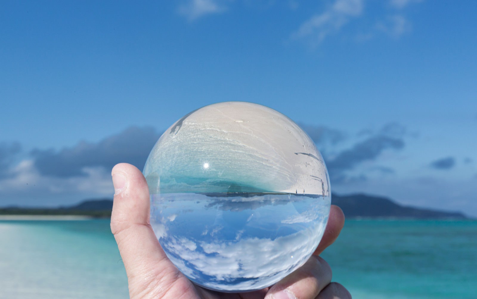「水晶玉に反転して映り込む南国の海」の写真