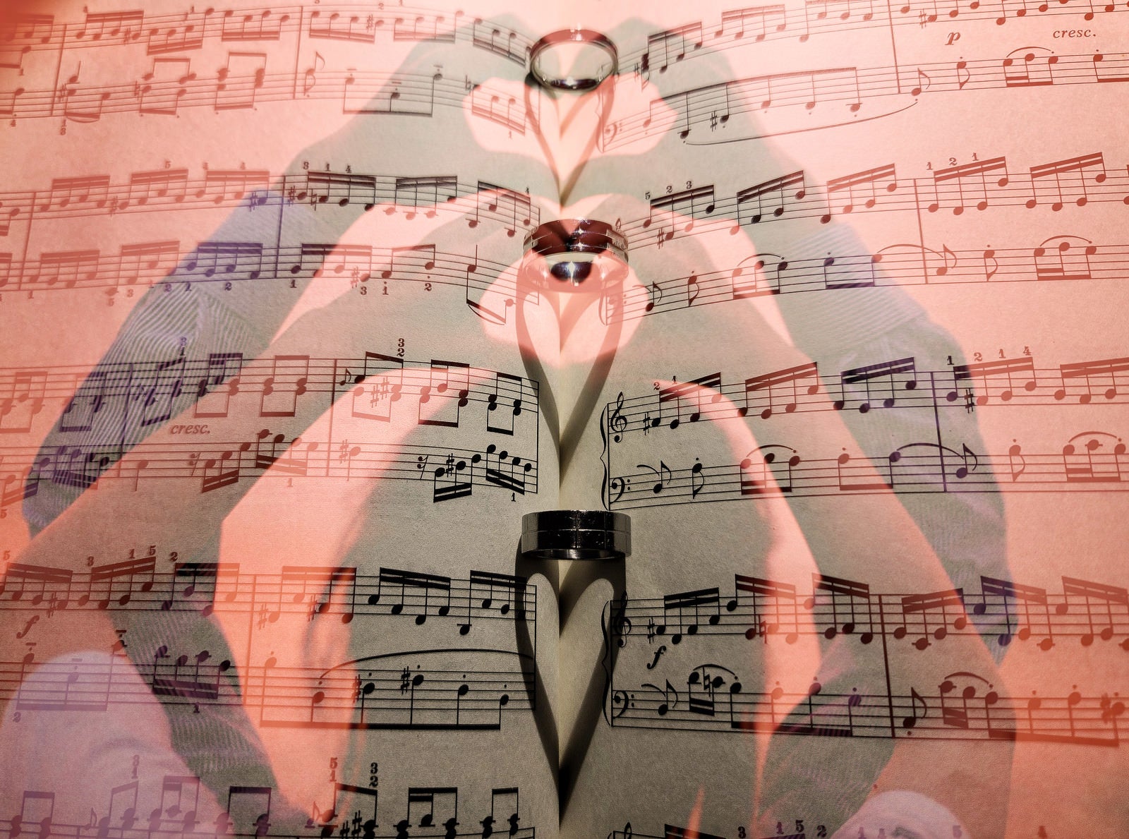 「楽譜に映るハートの影とハートのハンドサイン | フリー素材のぱくたそ」の写真
