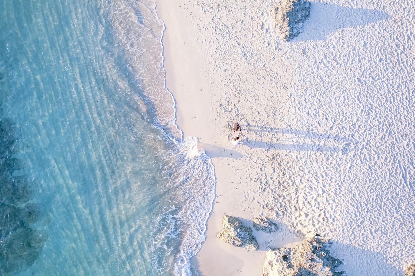 「ムスヌン浜の波打ち際を歩く観光客ふたり」の写真