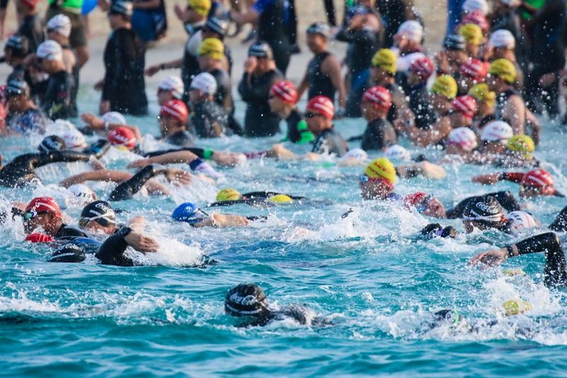 海上で競うトライアスロン選手たちの写真