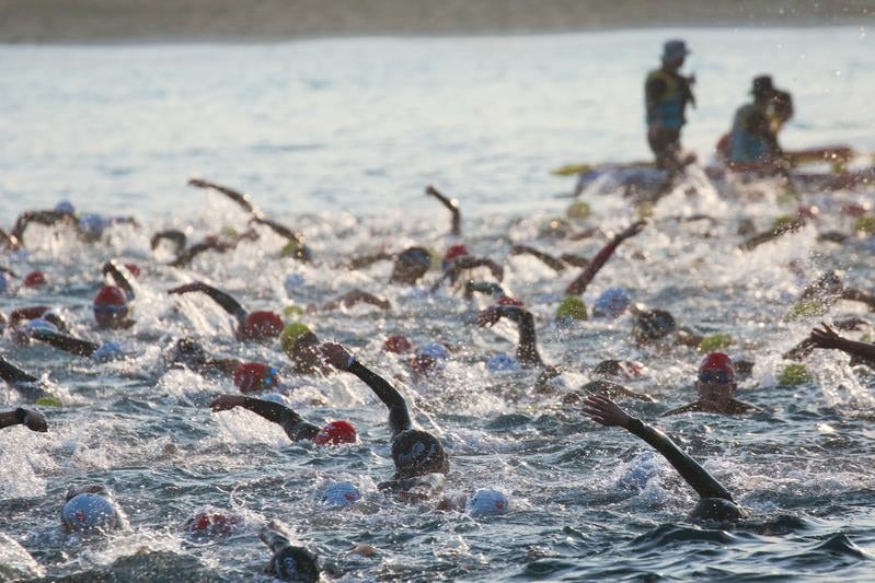 激しく水しぶきを上げるトライアスロン参加者たちの写真