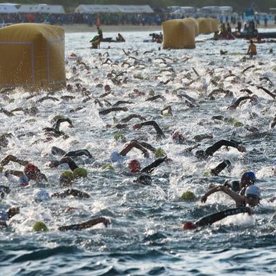 水しぶきを上げて競い合うトライアスロン選手たちの写真