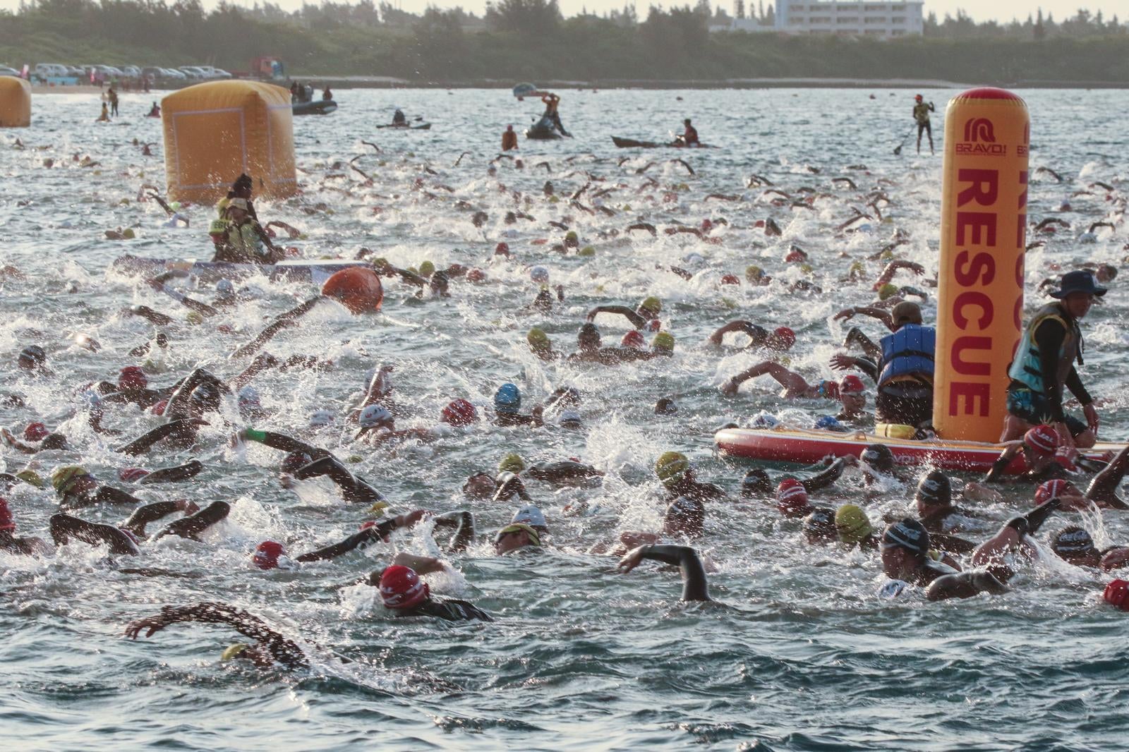 「トライアスロンで競い合う選手と浮かぶレスキュー隊」の写真