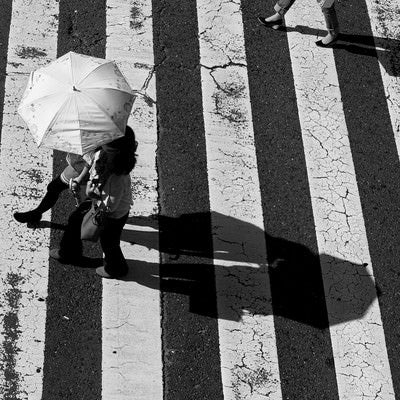 横断歩道を渡る日傘を差したカップルの写真